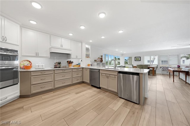 kitchen featuring kitchen peninsula, appliances with stainless steel finishes, decorative backsplash, sink, and white cabinets