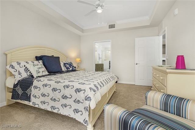 bedroom featuring ensuite bath, ceiling fan, a tray ceiling, light carpet, and ornamental molding