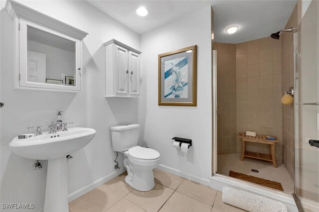 bathroom featuring tile patterned flooring, toilet, a tile shower, and sink