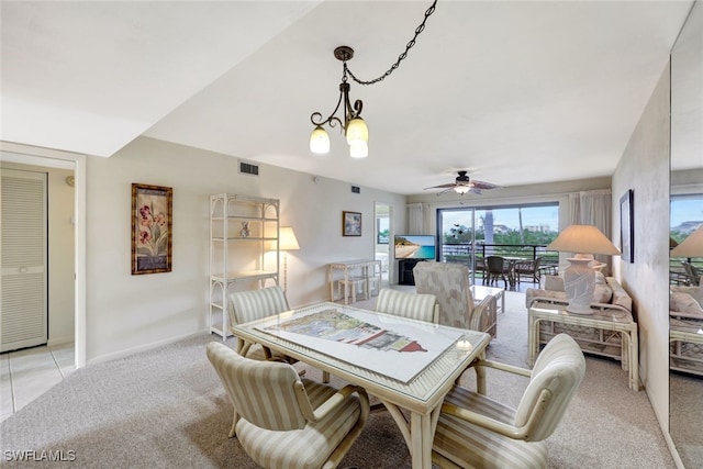 carpeted dining room with ceiling fan with notable chandelier