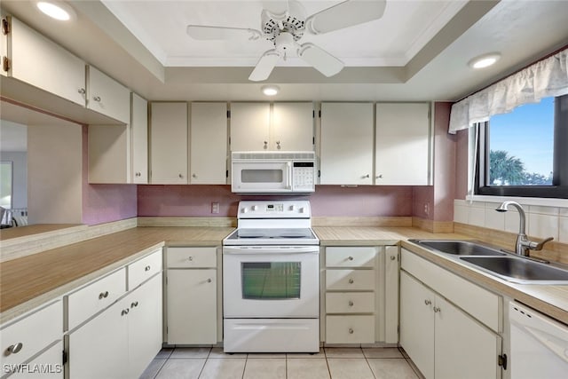 kitchen with sink, white appliances, a tray ceiling, and white cabinets