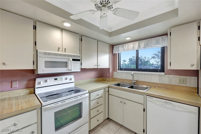 kitchen featuring sink, white appliances, crown molding, and a tray ceiling