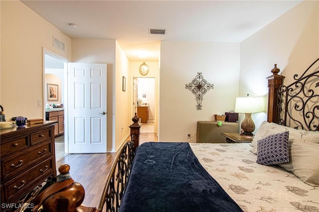 bedroom with wood-type flooring and connected bathroom