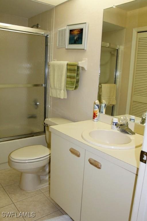 full bathroom with tile patterned flooring, vanity, combined bath / shower with glass door, and toilet