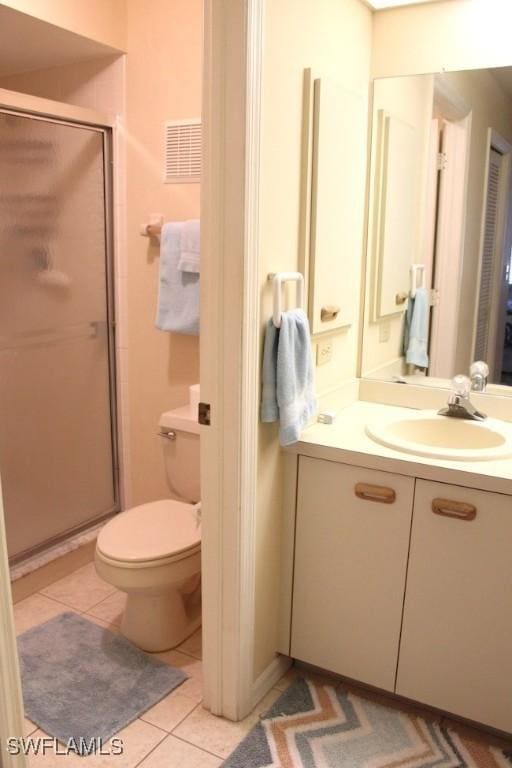 bathroom featuring tile patterned floors, toilet, vanity, and walk in shower