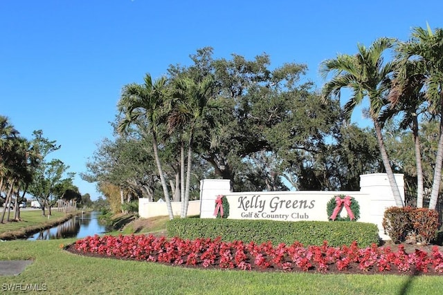 community sign featuring a lawn and a water view