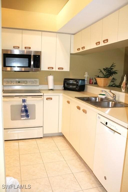 kitchen with white cabinets, light tile patterned floors, white appliances, and sink