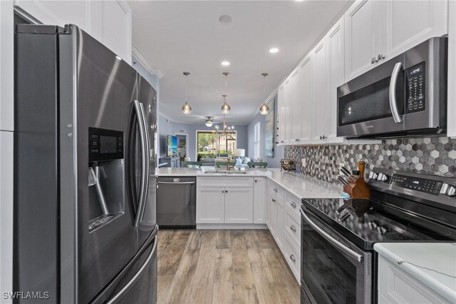 kitchen featuring kitchen peninsula, appliances with stainless steel finishes, pendant lighting, light hardwood / wood-style floors, and white cabinetry