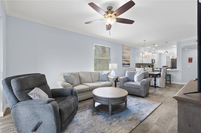 living room with light wood-type flooring, ceiling fan with notable chandelier, and crown molding