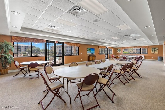 carpeted dining space featuring a drop ceiling