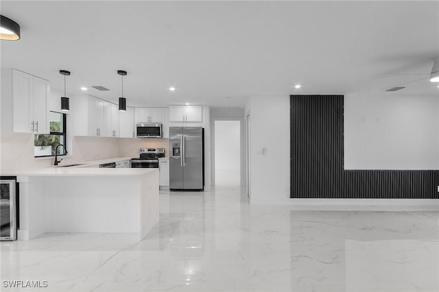 kitchen with stainless steel appliances, kitchen peninsula, white cabinets, decorative light fixtures, and sink