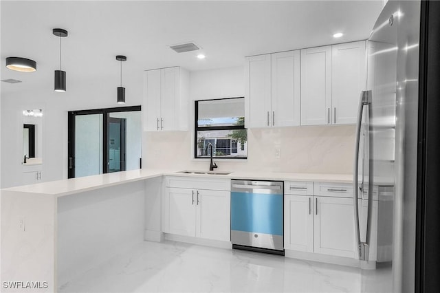 kitchen with appliances with stainless steel finishes, hanging light fixtures, kitchen peninsula, white cabinets, and sink