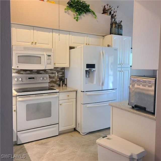 kitchen with decorative backsplash, light tile patterned floors, white cabinets, and white appliances