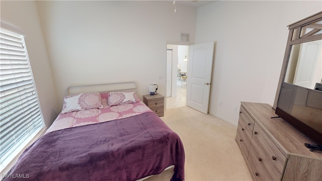 bedroom featuring light carpet and a high ceiling