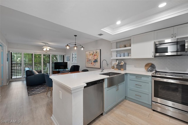 kitchen with decorative light fixtures, sink, kitchen peninsula, and stainless steel appliances