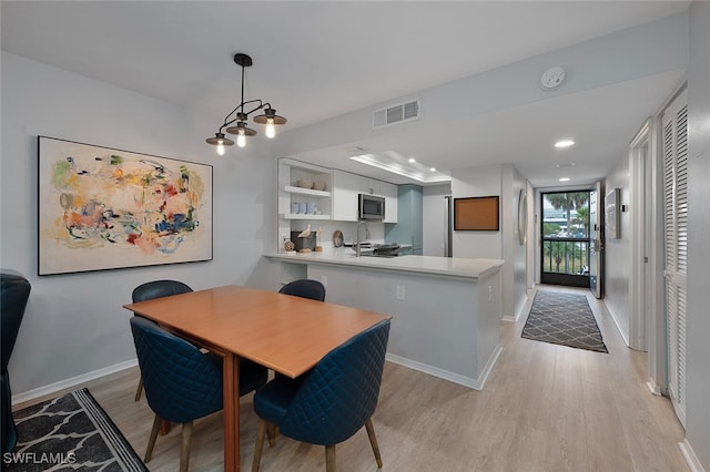 dining area with light wood-type flooring, expansive windows, and sink