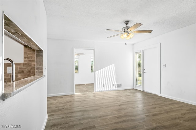 spare room with plenty of natural light, a textured ceiling, ceiling fan, and dark hardwood / wood-style floors