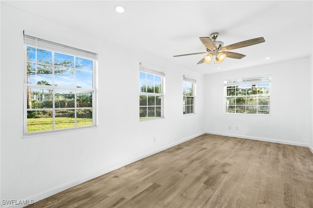 spare room featuring ceiling fan, a wealth of natural light, and wood-type flooring