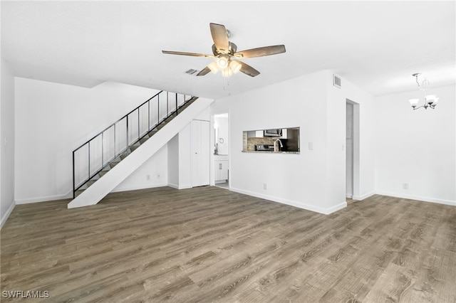 unfurnished living room featuring ceiling fan with notable chandelier and wood-type flooring