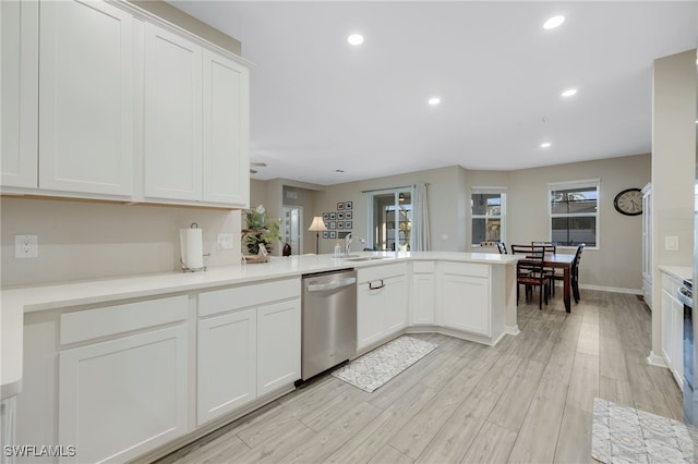 kitchen with sink, dishwasher, white cabinets, kitchen peninsula, and light wood-type flooring