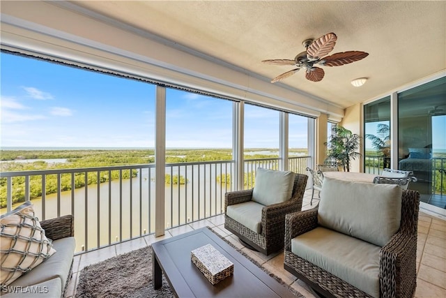 sunroom / solarium with ceiling fan and a water view