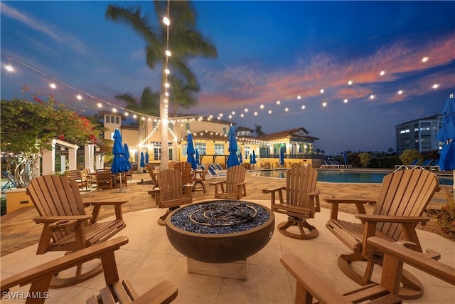 patio terrace at dusk with a community pool and a fire pit