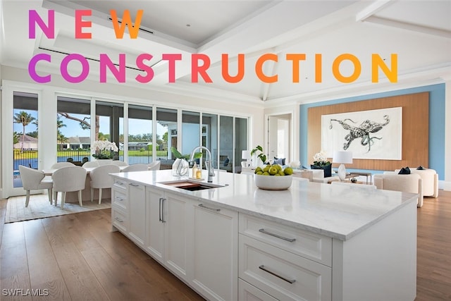 kitchen featuring white cabinetry, sink, dark wood-type flooring, and a center island with sink