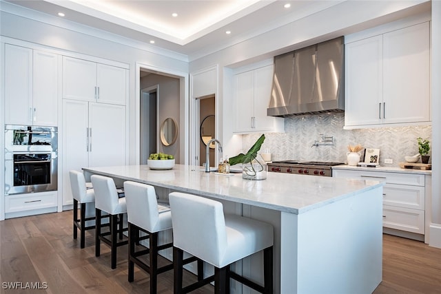 kitchen with dark wood-style flooring, stove, double oven, a sink, and wall chimney range hood