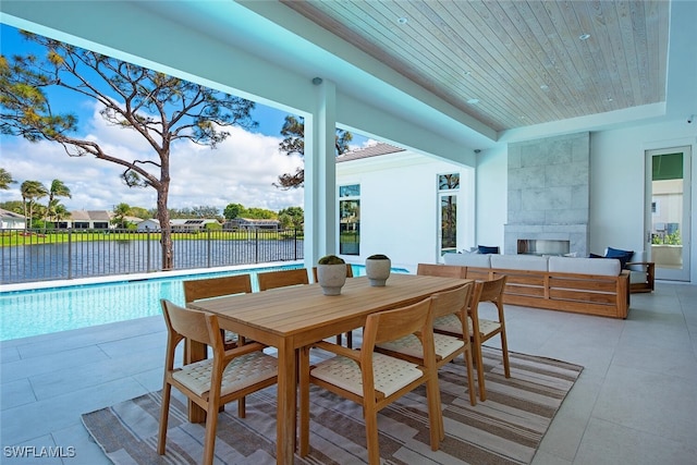 exterior space with light tile patterned flooring, a tiled fireplace, a raised ceiling, and wooden ceiling