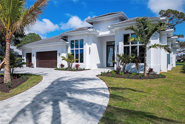 view of front of home with a garage, stucco siding, a tile roof, decorative driveway, and a front yard