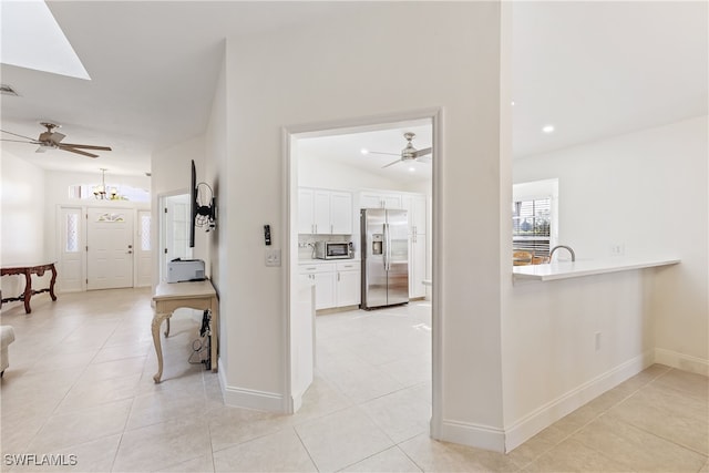 corridor featuring vaulted ceiling with skylight and light tile patterned flooring