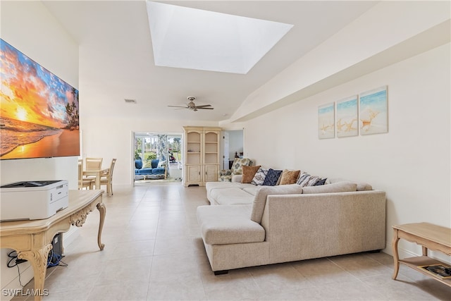 living room with ceiling fan, light tile patterned floors, and lofted ceiling with skylight