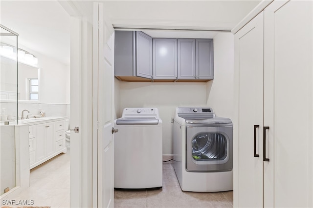 laundry room featuring light tile patterned floors, washing machine and dryer, and cabinets