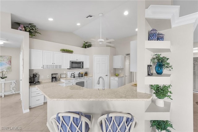 kitchen with white range with electric stovetop, white cabinetry, kitchen peninsula, and a breakfast bar area