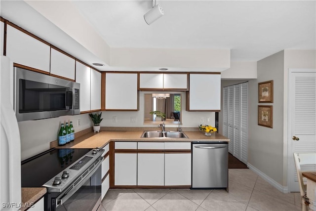 kitchen with white cabinetry, stainless steel appliances, sink, and light tile patterned floors