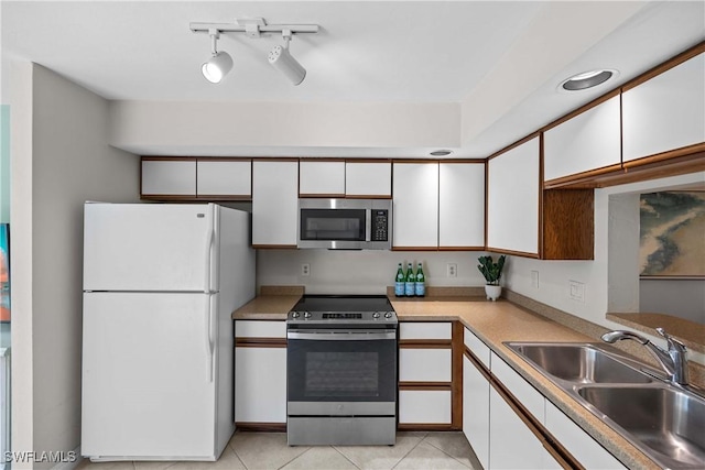 kitchen with sink, light tile patterned floors, white cabinetry, stainless steel appliances, and track lighting