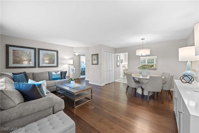 living room with plenty of natural light, dark hardwood / wood-style floors, and an inviting chandelier