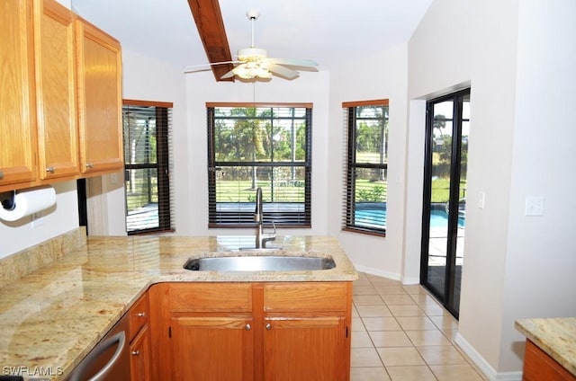 kitchen featuring light stone countertops, kitchen peninsula, ceiling fan, light tile patterned floors, and sink