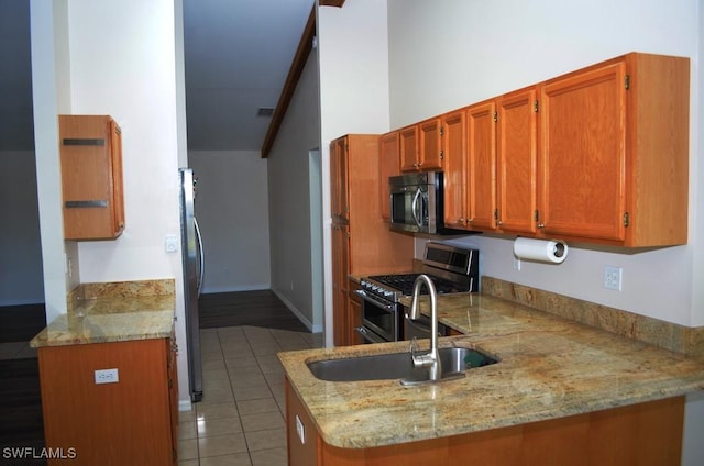 kitchen featuring stainless steel appliances, light stone counters, and kitchen peninsula