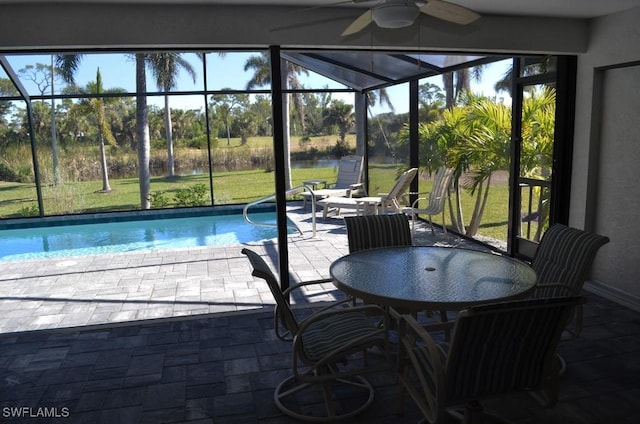 view of swimming pool featuring ceiling fan, a patio, glass enclosure, and a yard