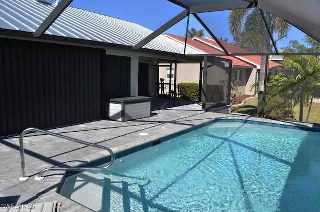 view of pool with a patio area, ceiling fan, and glass enclosure