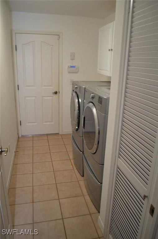 laundry area with washer and dryer, cabinets, and light tile patterned floors