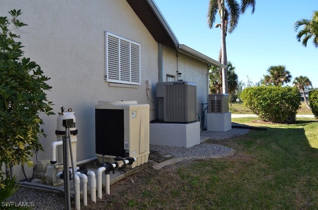 view of side of property with central AC and a lawn