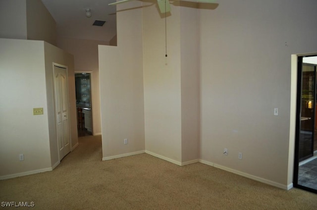 carpeted spare room with ceiling fan and high vaulted ceiling