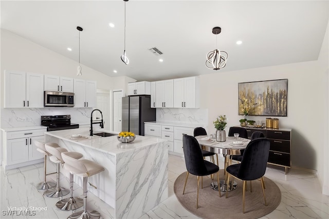 kitchen with light stone counters, an island with sink, pendant lighting, decorative backsplash, and appliances with stainless steel finishes