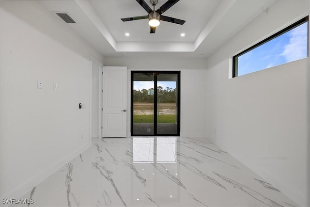 spare room with ceiling fan and a tray ceiling