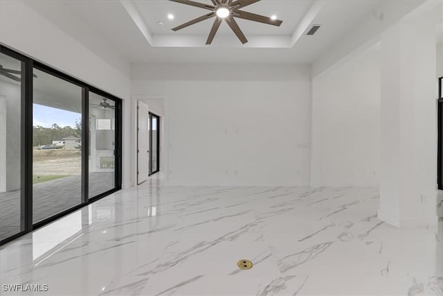 unfurnished room with ceiling fan and a raised ceiling