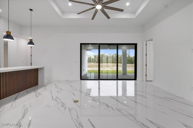 empty room with ceiling fan and a tray ceiling