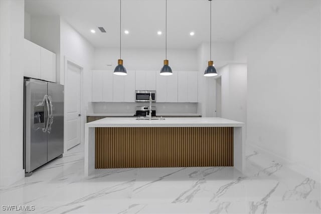 kitchen with white cabinetry, appliances with stainless steel finishes, pendant lighting, and a center island with sink