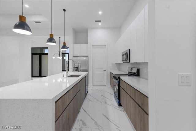 kitchen with a large island with sink, appliances with stainless steel finishes, white cabinetry, decorative backsplash, and hanging light fixtures